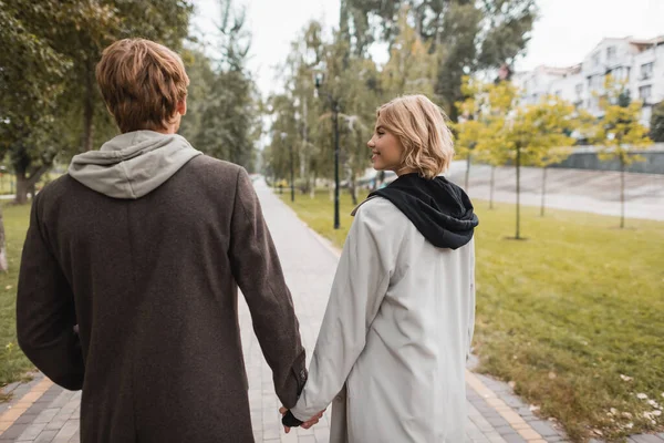 Gioiosa Donna Bionda Guardando Uomo Allegro Mentre Tiene Mano Passeggia — Foto Stock