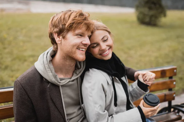 Happy Young Man Hugging Cheerful Girlfriend Holding Paper Cup While — Stock Photo, Image