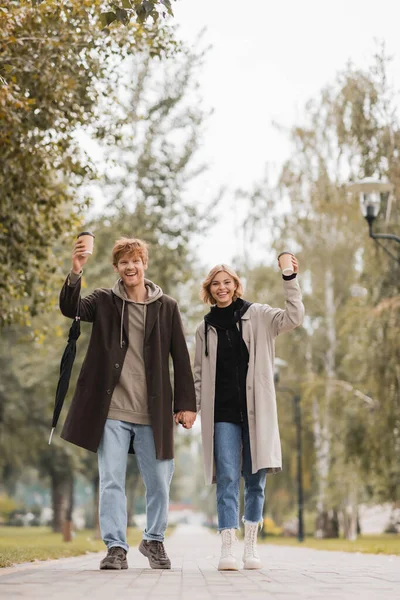 Full Length Joyful Couple Coats Holding Hands Walking Paper Cups — Stock Photo, Image