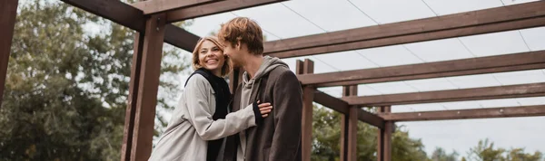 Happy Young Couple Autumnal Coats Hugging Multiple Arch Park Banner — Stock Photo, Image