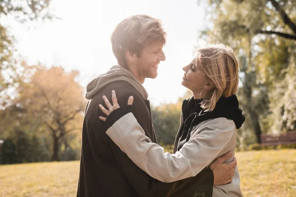 Widok Boku Młoda Szczęśliwa Para Uśmiechnięta Podczas Przytulania Jesiennym Parku — Zdjęcie stockowe