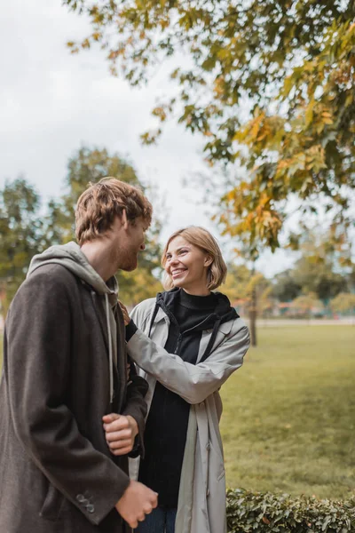 约会期间 穿着外套的夫妻在秋天的公园散步时互相望着对方 心里很高兴 — 图库照片