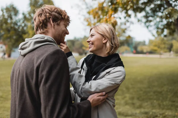 Pleased Couple Coats Looking Each Other While Hugging Autumnal Park — Stock Photo, Image