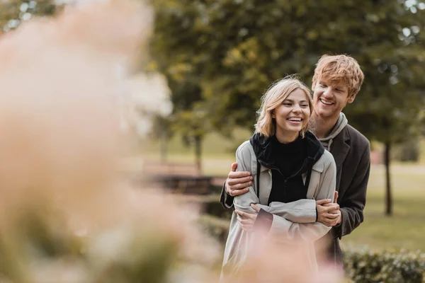 在公园里 红头发的男人一边拥抱快乐的女人 一边微笑着约会 — 图库照片
