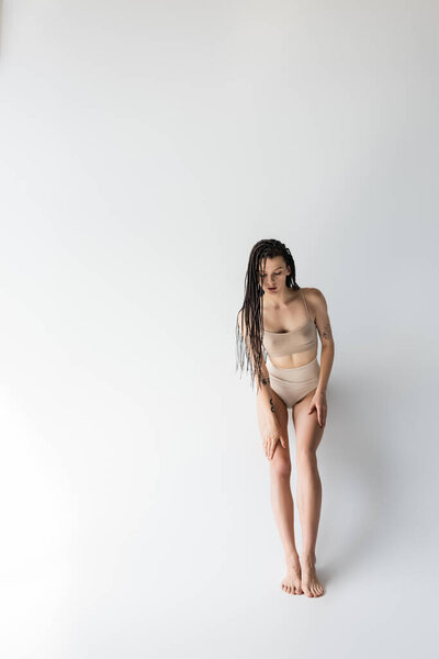 Full length of young fit woman in underwear on grey background 