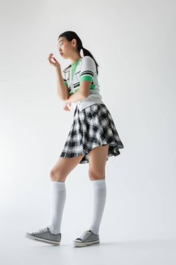 Diz altı çoraplı genç Asyalı kadının gri arka plandan bakışları düşük açı. 