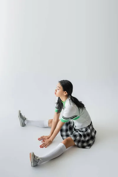 Elegante Mujer Asiática Falda Calcetines Rodilla Sentado Sobre Fondo Gris — Foto de Stock