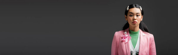 Модная азиатская модель в куртке, стоящая изолированная на сером, баннере 