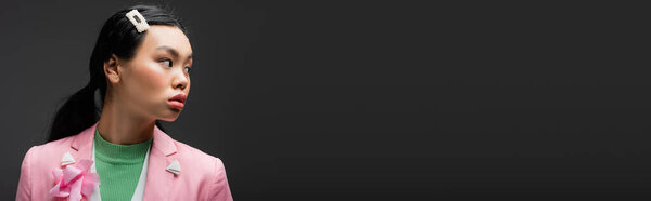 Брюнетка азиатская женщина в розовой куртке смотрит в сторону изолированы на серый с копировальным пространством, баннер 