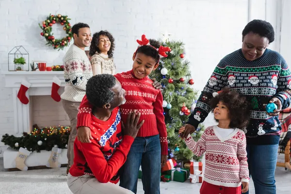 Happy african american grandparents talking to kids in living room with christmas tree — Stock Photo