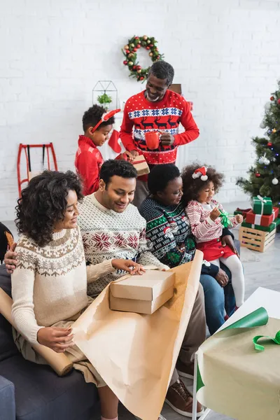 Fröhliche afrikanisch-amerikanische Familie packt Weihnachtsgeschenke zu Hause zusammen — Stockfoto