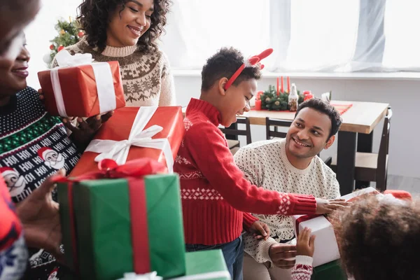 Весела афроамериканська сім'я тримає різдвяні подарунки у вітальні — стокове фото