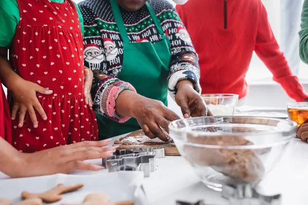 Vista cortada da mulher afro-americana de meia idade preparando pastelaria de natal perto da família — Fotografia de Stock