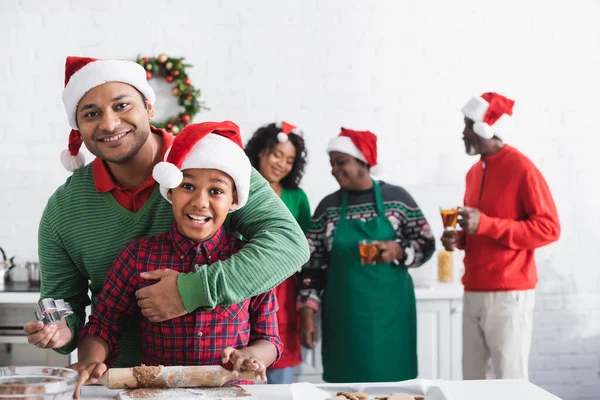 Afrikanisch-amerikanischer Mann umarmt aufgeregten Sohn, während er Ausstecher in der Küche hält — Stockfoto