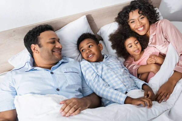 High angle view of cheerful african american family lying in bed in morning — Stock Photo