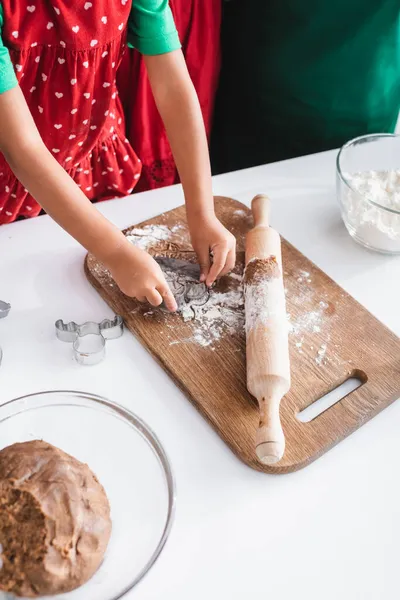 Abgeschnittene Ansicht eines afrikanisch-amerikanischen Mädchens, das Teig mit Ausstecher in Rentierkopfform schneidet — Stockfoto