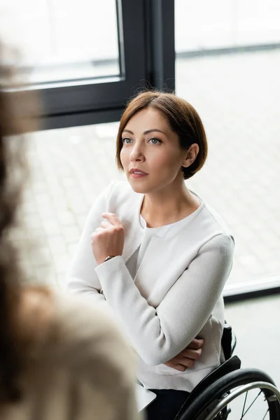 Businesswoman with disability looking at blurred colleague in office — Stock Photo