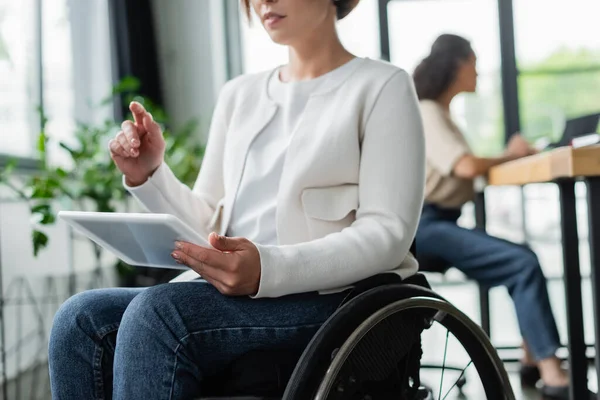 Verschwommene Geschäftsfrau im Rollstuhl zeigt im Büro mit dem Finger auf digitales Tablet — Stockfoto