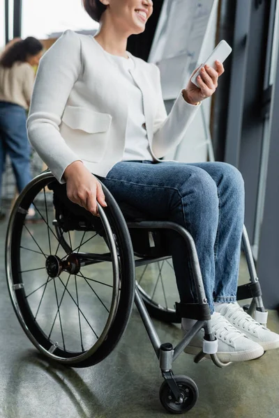 Visão cortada de empresária feliz com deficiência física usando telefone celular no escritório — Fotografia de Stock