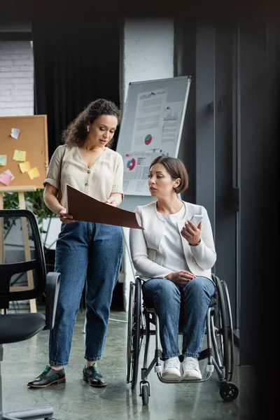 African american businesswoman showing documents to colleague with disability in office — Stock Photo