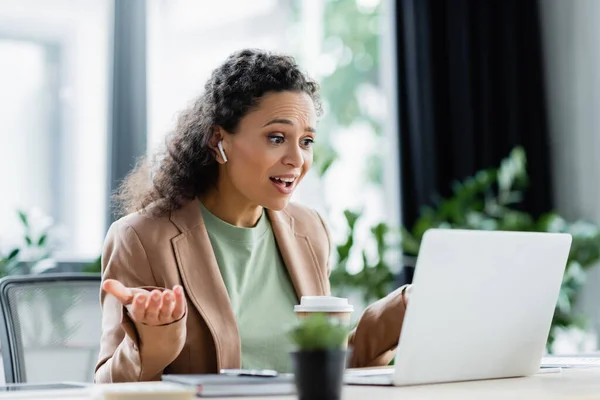 Surprised african american businesswoman gesturing during video chat on laptop in office — Stock Photo