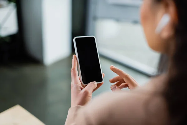 Cropped view of blurred african american businesswoman pointing at smartphone with blank screen in office — Stock Photo