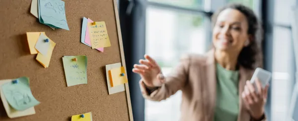 Selective focus of corkboard with paper notes near blurred african american businesswoman, banner — Stock Photo