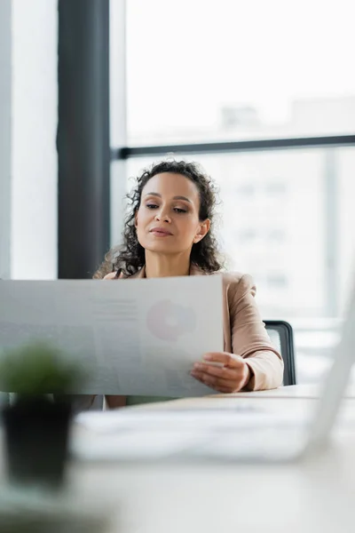 Mujer de negocios afroamericana que trabaja con documento en la oficina en primer plano borroso - foto de stock