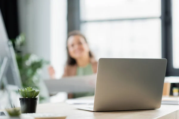 Selektiver Fokus des Laptops auf dem Schreibtisch in der Nähe einer afrikanisch-amerikanischen Geschäftsfrau auf verschwommenem Hintergrund — Stockfoto