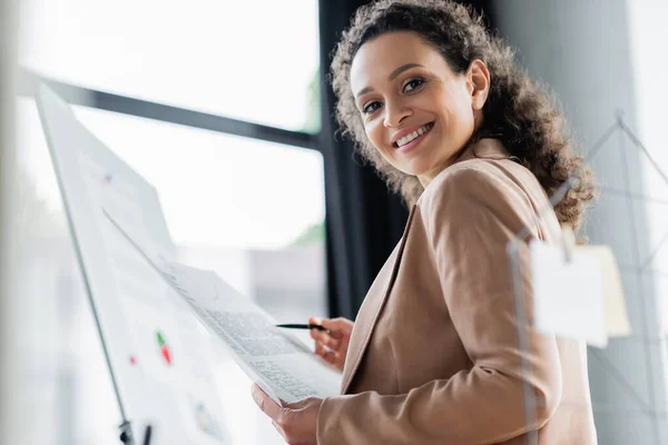 Low angle view of happy african american businesswoman working with papers in office — Stock Photo