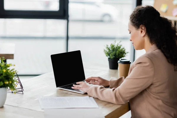 Afro-américaine femme d'affaires tapant sur ordinateur portable avec écran blanc au bureau — Photo de stock