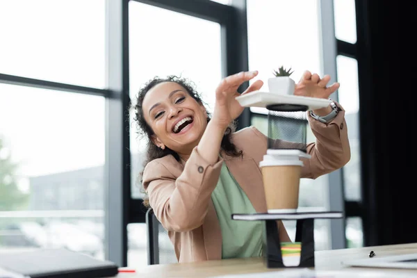 Aufgeregte afrikanisch-amerikanische Geschäftsfrau lacht in die Kamera, während sie Spaß am Arbeitsplatz im Büro hat — Stockfoto