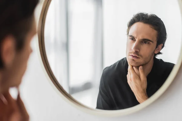 Uomo sfocato in vestaglia nera guardando lo specchio a casa — Foto stock