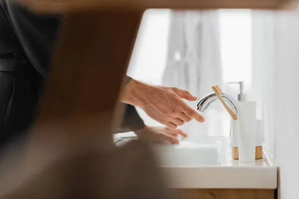 Ausgeschnittene Ansicht eines Mannes, der neben Zahnbürste auf Waschbecken im Badezimmer steht — Stockfoto