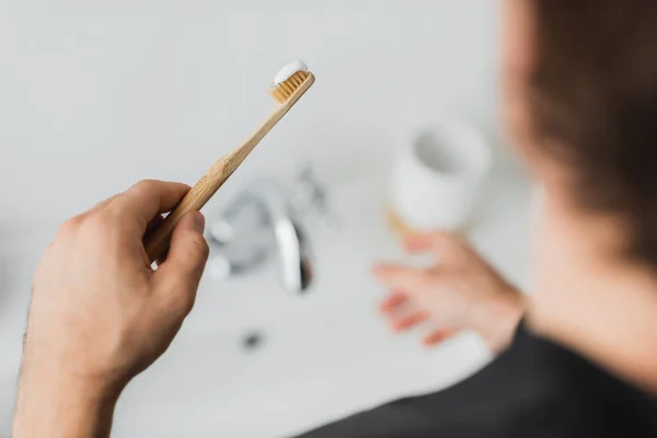 Blurred man holding toothbrush and toothpaste in bathroom — Stock Photo