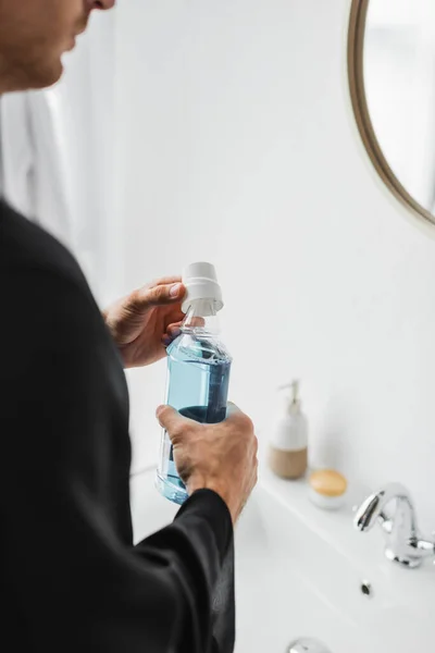 Vista recortada del hombre sosteniendo la botella de enjuague bucal en el baño - foto de stock