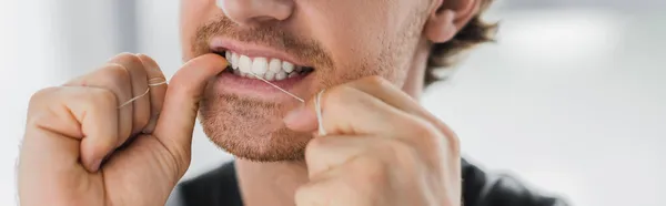 Vista ritagliata dell'uomo che pulisce i denti con filo interdentale a casa, banner — Foto stock