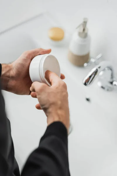 Cropped view of man taking cosmetic cream from jar in bathroom — Stock Photo