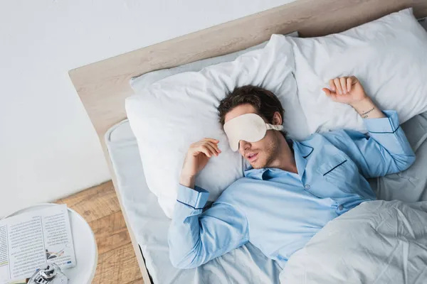 Draufsicht des Mannes mit Schlafmaske, der morgens auf dem Bett schläft — Stockfoto