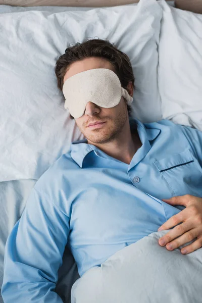 Top view of man in pajama and sleep mask sleeping on bed at home — Stock Photo