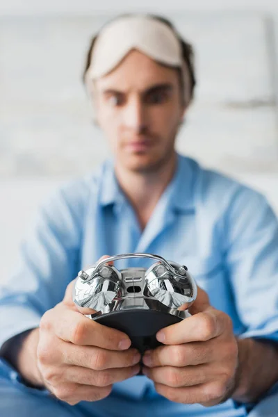 Alarm clock in hands of blurred man in pajama at home — Stock Photo