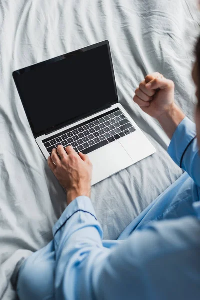 Vista superior de freelancer borroso en pijama mostrando sí gesto mientras se utiliza el ordenador portátil en la cama - foto de stock