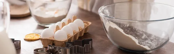 Tagliabiscotti vicino uova e farina in cucina, banner — Foto stock