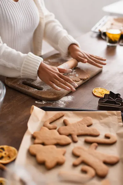 Vue recadrée de la femme afro-américaine rouler la pâte près de biscuits de Noël et coupe-biscuits — Photo de stock