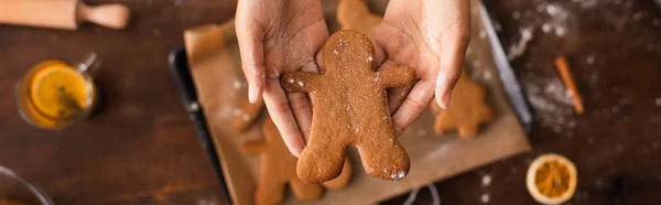 Top view of african american woman holding christmas gingerbread near blurred tray in kitchen, banner — Stock Photo