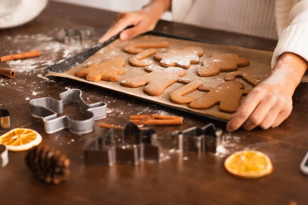 Vista cortada da mulher americana africana segurando bandeja com biscoitos de Natal perto de paus de canela — Fotografia de Stock