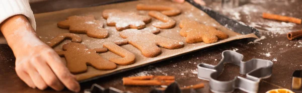 Vista cortada da mulher americana africana com mão na farinha segurando bandeja com biscoitos de Natal e canela, banner — Fotografia de Stock