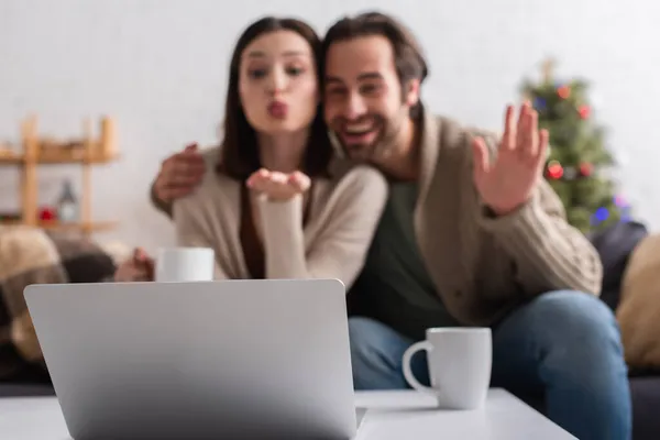 Coppia sfocata agitando mano e soffiando aria bacio durante la videochiamata sul computer portatile — Foto stock