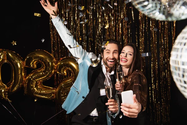Elegant woman taking selfie with excited man while celebrating christmas on black — Stock Photo