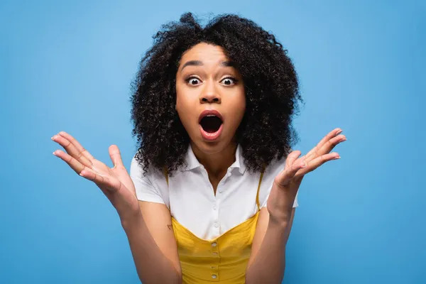 Amazed african american woman with open mouth showing wow gesture isolated on blue — Stock Photo